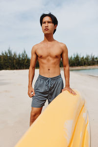 Portrait of shirtless man standing at beach