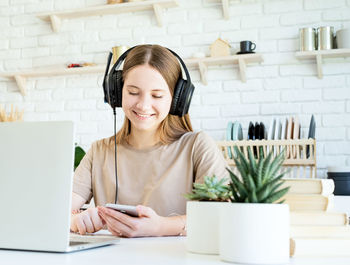 Young woman using phone while sitting on table