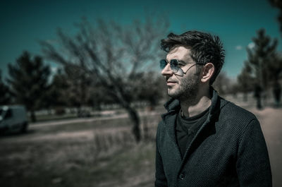 Portrait of young man standing against trees