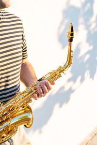 Midsection of man holding saxophone