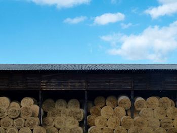 Rolled hay bales at barn against sky