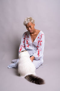 Full length of a young woman sitting against white background