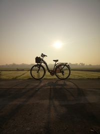 Bicycle on field against sky during sunset