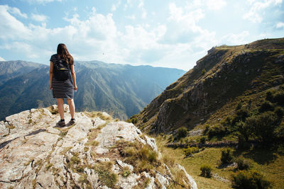 Rear view of man standing on mountain against sky