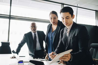 Young businessman discussing with colleagues over digital tablet in conference room at office