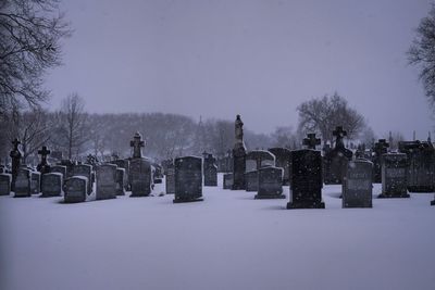 Snow covered cemetery against clear sky