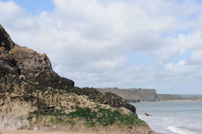 Scenic view of sea by cliff against sky