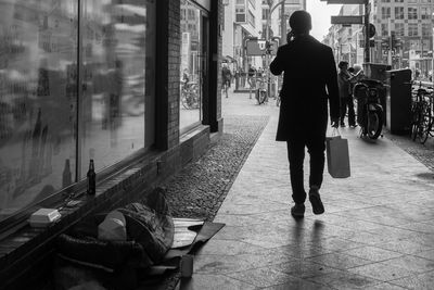 Rear view of man walking on street in city