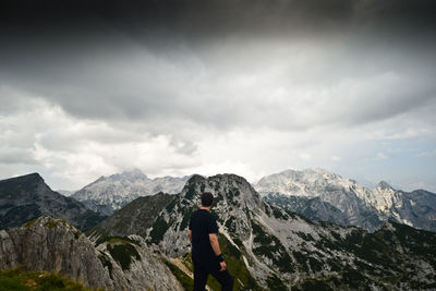Rear view of man standing on snowcapped mountain