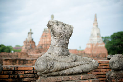Damaged statues in temple against sky
