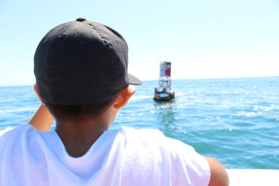 Rear view of man sailing in sea against clear sky