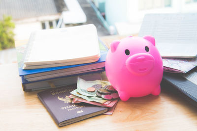 High angle view of money with piggybank and passport by books on table