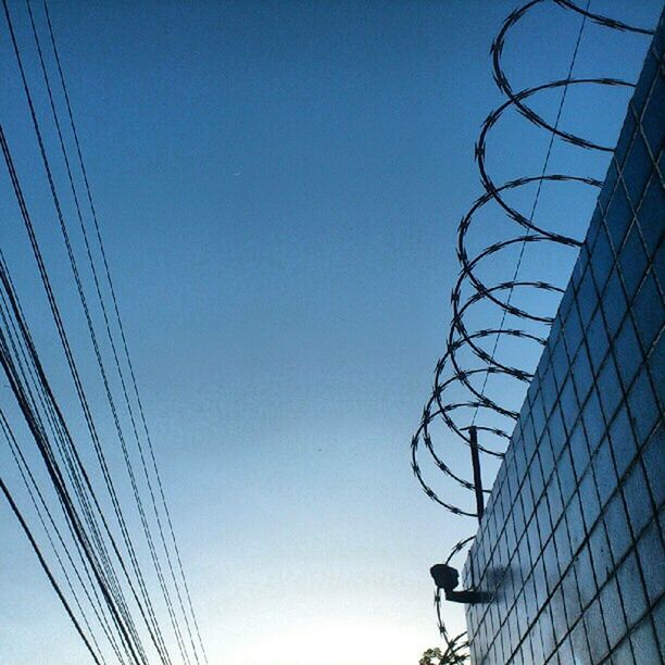 low angle view, clear sky, built structure, architecture, building exterior, blue, power line, cable, connection, copy space, city, modern, building, office building, outdoors, day, tall - high, sky, high section, no people