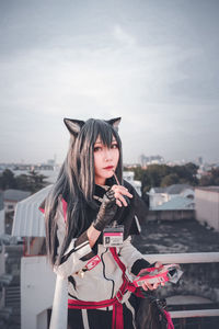 Portrait of beautiful woman standing against city in background