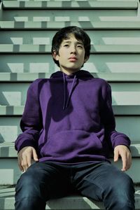 Full length of a young man sitting against wall