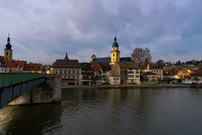 Bridge over river by buildings against sky in city