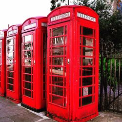 Red telephone booth against sky