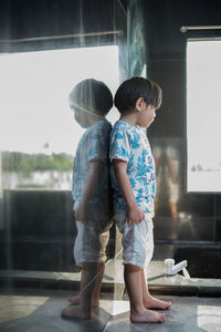 Side view of boy standing by wall