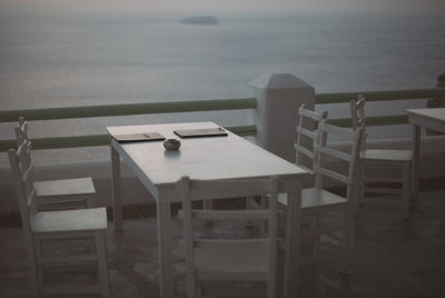 Chairs and table by sea against sky