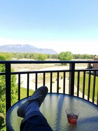 Low section of woman standing on cliff against clear sky