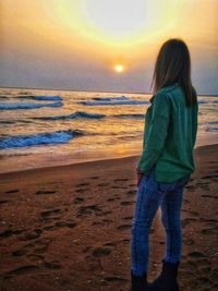 Woman standing on beach during sunset