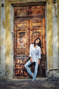 Portrait of woman standing against rusty door