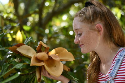 Young girl smelling a large yellow flower, side view