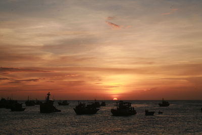 Silhouette sailboats in sea against sky during sunset