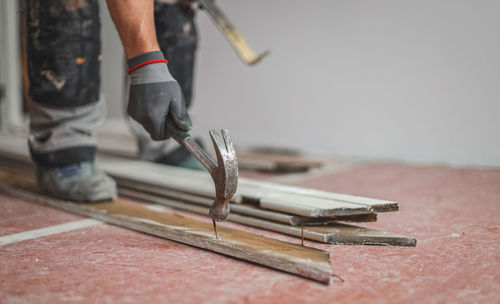 Human pulls out a nail from a board.