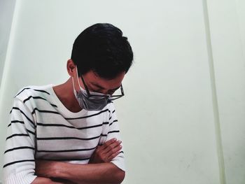 Young man looking away while sitting on wall