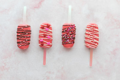 Alternating up and down facing valentine cakesicles on a pink marble surface.