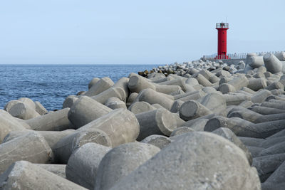 Lighthouse by sea against clear sky