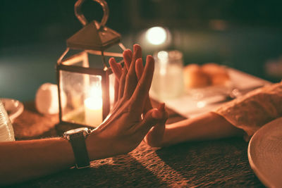 Close-up of couple holding hands on illuminated table