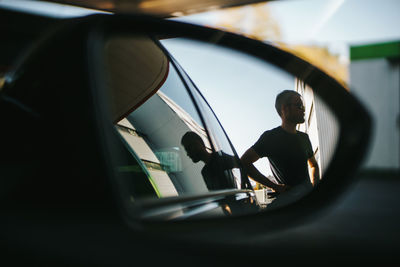 Reflection of man on side-view mirror of car