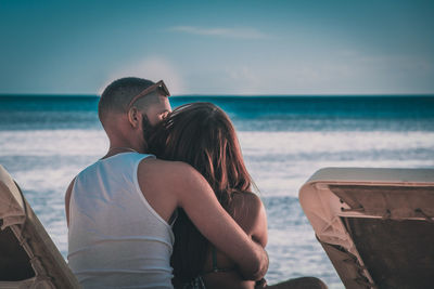 Rear view of couple kissing against sea