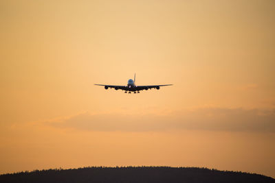 Low angle view of silhouette airplane against sky during sunset