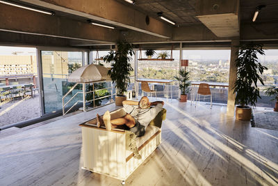 Relaxed mature man lying on sofa at building terrace during sunset