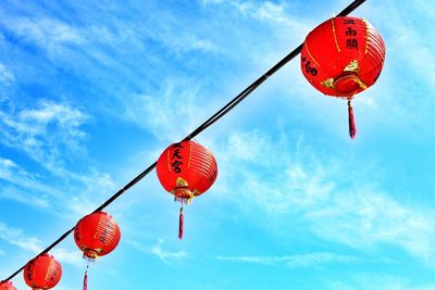 Low angle view of chinese lanterns hanging against blue sky