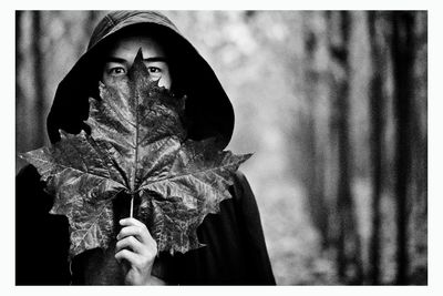 Man covering face with leaf while standing outdoors