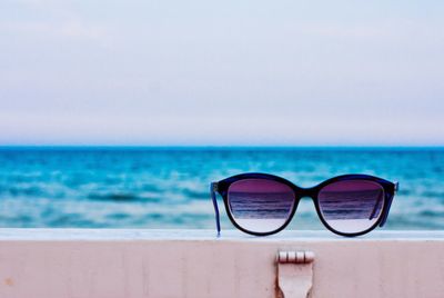 Close-up of sunglasses on retaining wall against sea