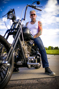 Man sitting on motorcycle against sky