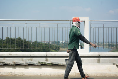 Full length of man standing on railing against sky