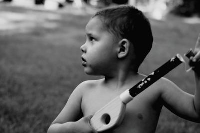 Close-up of shirtless boy holding toy gun on field