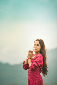 Portrait of smiling woman standing against sky