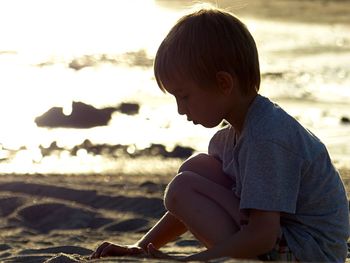 Side view of boy sitting on beach