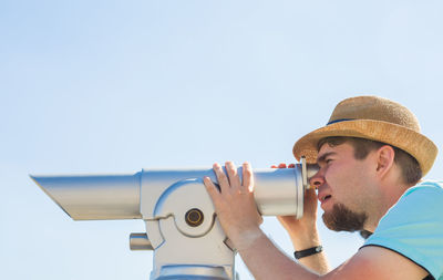 Side view of man photographing against clear sky