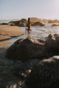 Rear view of man walking on rock at beach