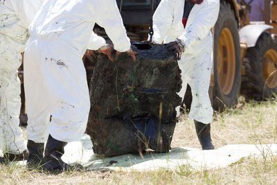 Low section of workers holding garbage on field