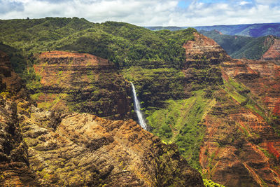 Scenic view of waterfall and mountains against sky