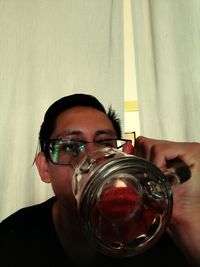 Close-up portrait of a young man holding eyeglasses